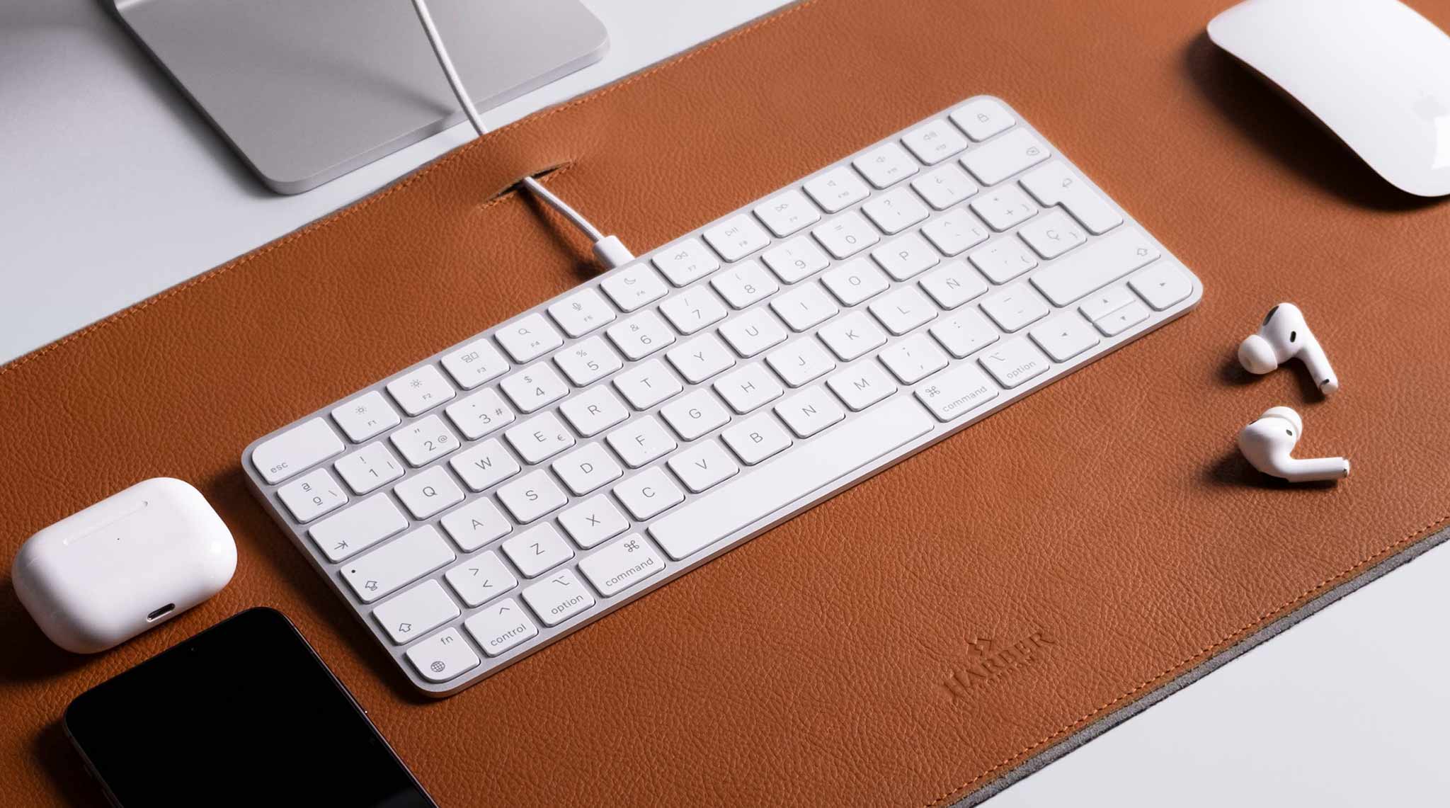 Teclado Apple sobre una alfombrilla de escritorio de cuero plena flor