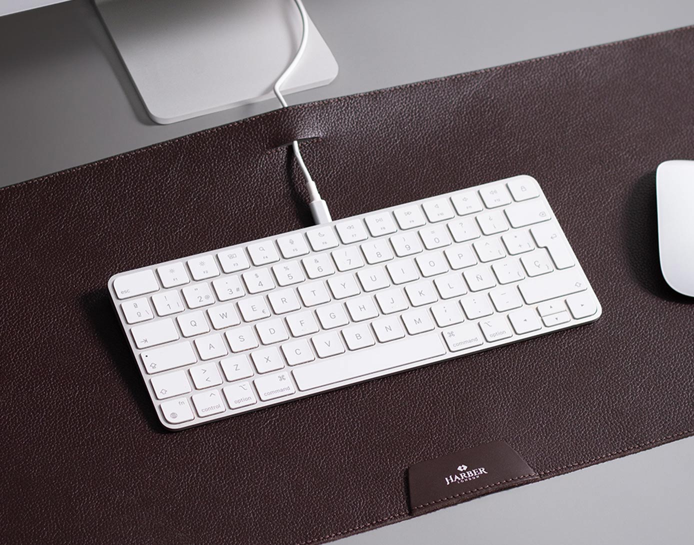 White keyboard on a brown leather desk mat with a mouse to the right